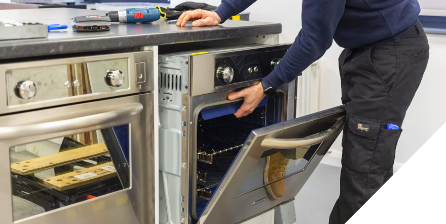 An electrician installing new electric ovens in a kitchen